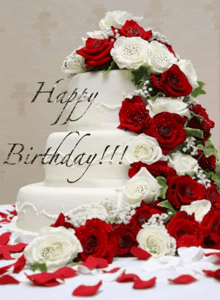 Eine mehrstöckige weiße Torte mit roten und weißen Rosen sowie verstreuten Blütenblättern trägt "Happy Birthday!!!".