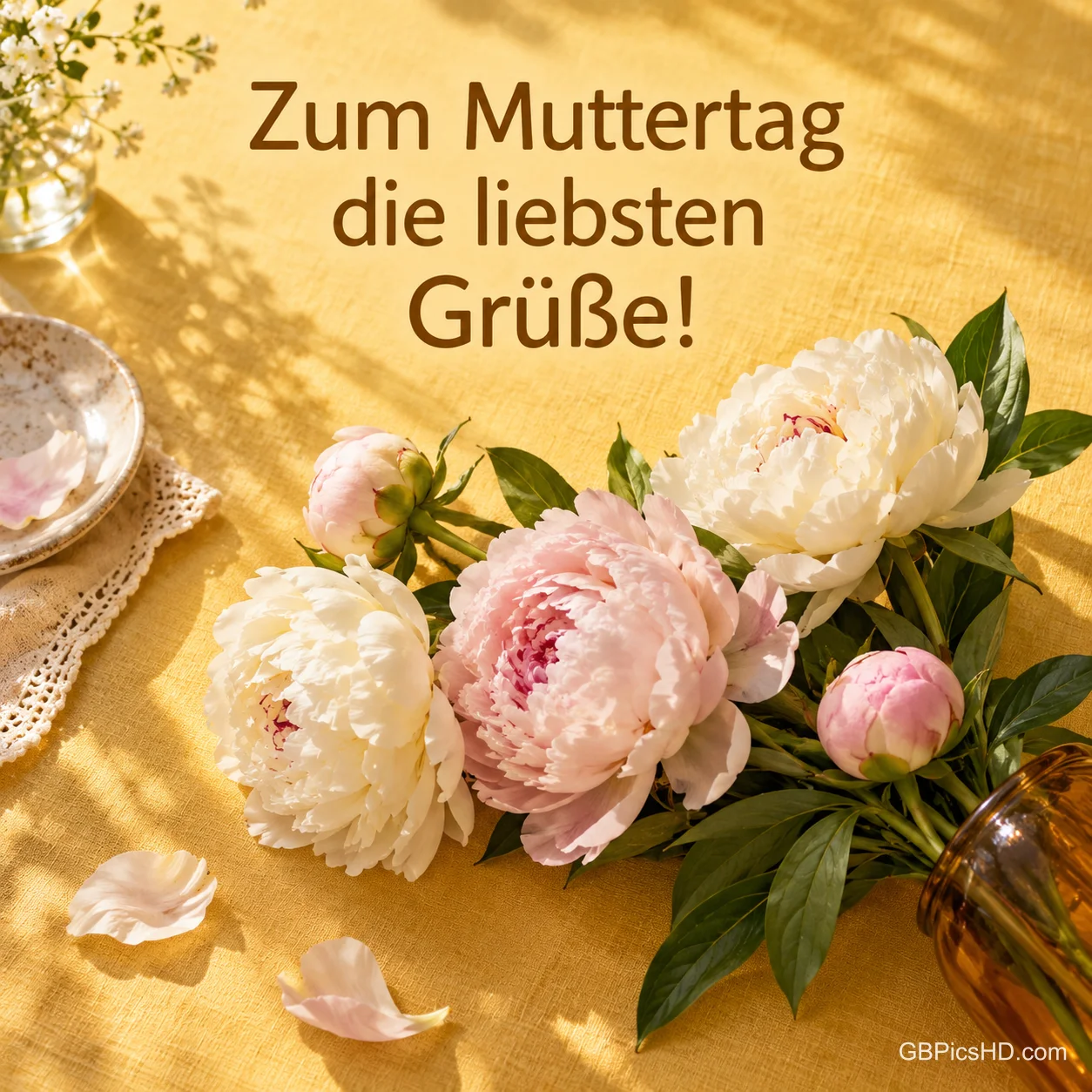Weiße und rosa Pfingstrosen auf einer sonnigen gelben Tischdecke mit dem Text "Zum Muttertag die liebsten Grüße!". Weiße und rosa Pfingstrosen auf einer sonnigen gelben Tischdecke mit dem Text "Zum Muttertag die liebsten Grüße!".