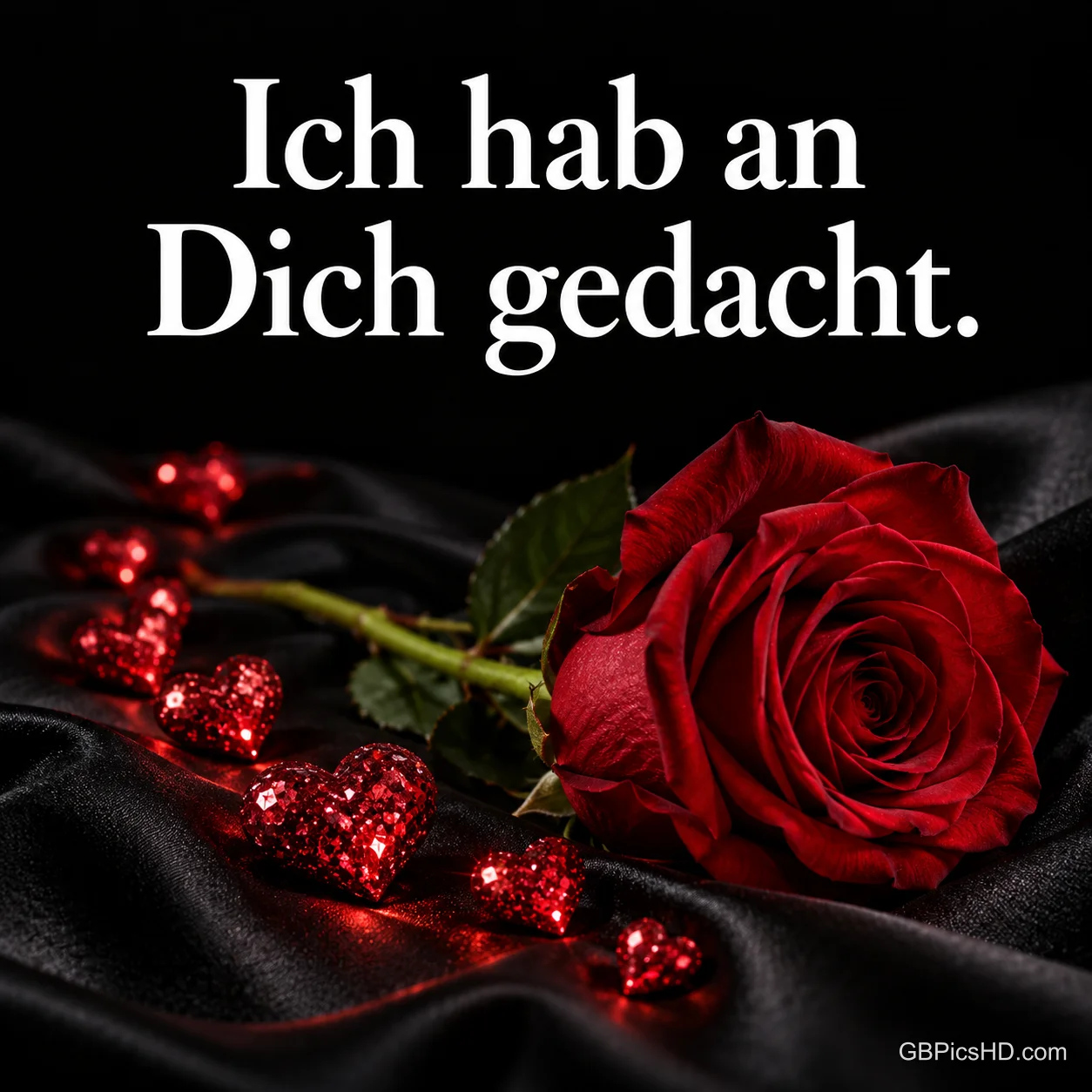 Eine rote Rose und glitzernde Herzen auf schwarzem Satin mit dem Text "Ich hab an Dich gedacht.". Eine rote Rose und glitzernde Herzen auf schwarzem Satin mit dem Text "Ich hab an Dich gedacht.".