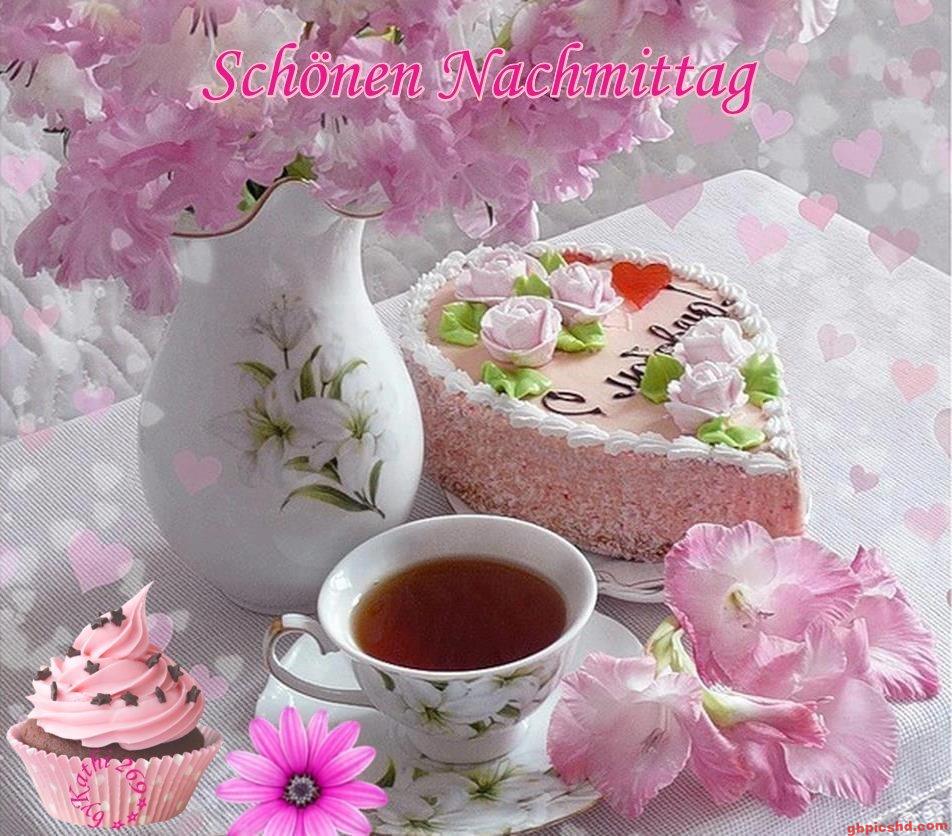 Geburtstagskuchen, Tee und springende rosa Blumen auf weißem Tisch, angenehme Nachmittagsstimmung.