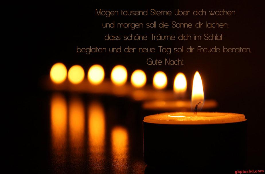 Brennende Kerzen im Dunkeln mit einem Gute-Nacht-Wunsch in deutscher Sprache.