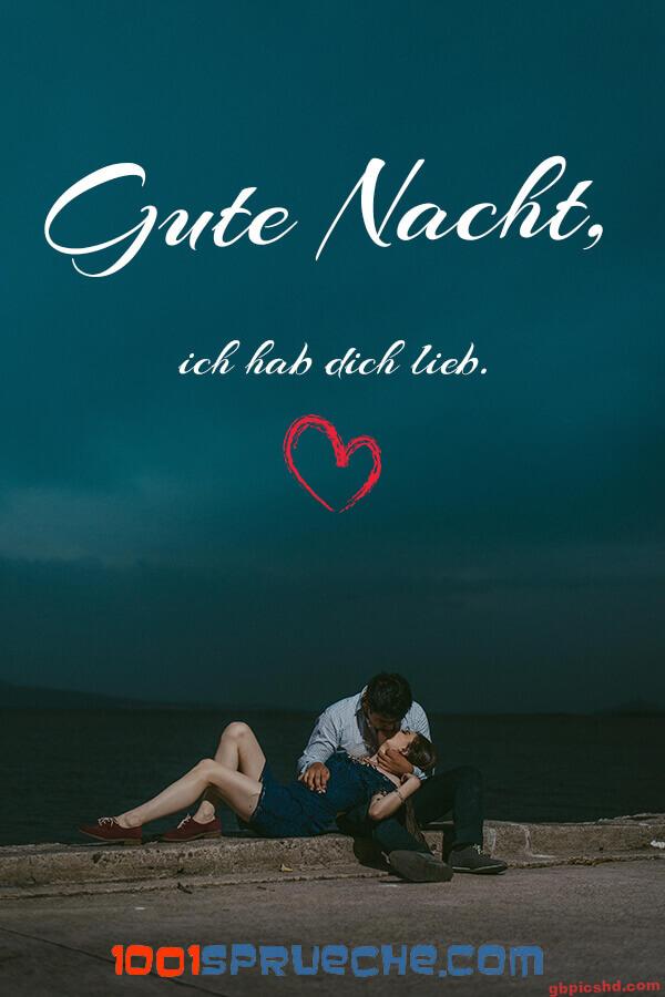 Paar sitzt am Wasser bei Nacht, der Mann küsst die Frau, romantische Stimmung.